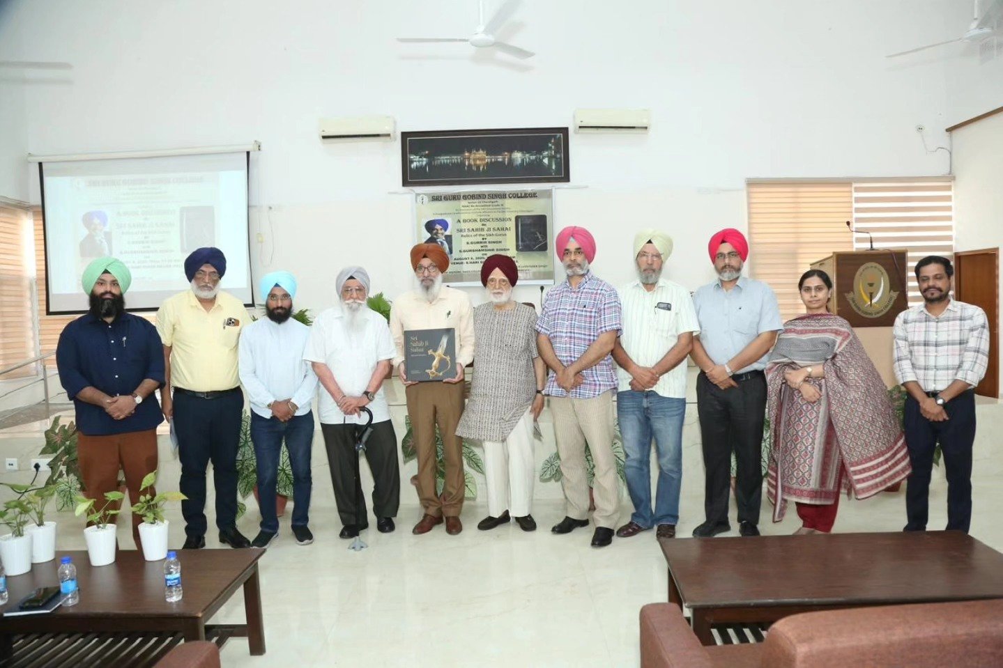 S. Gurbir Singh presents his book to the Principal, SGGS College, in the presence of management members and faculty.